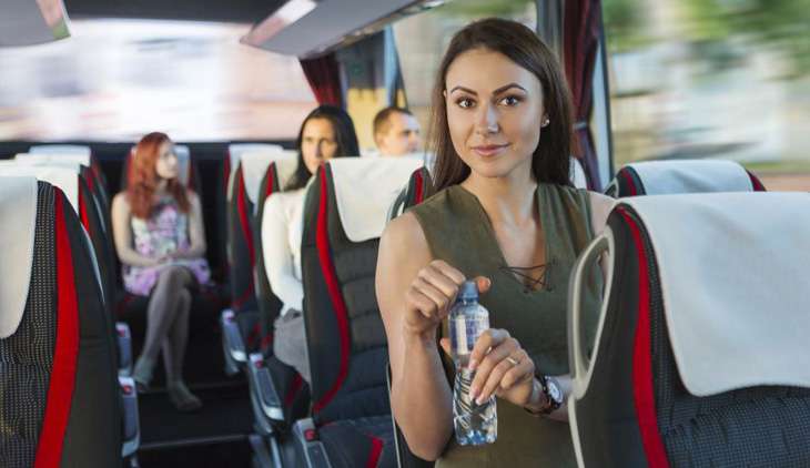 Девушка едет в автобусе и держит бутылку с водой